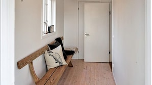 A hallway with a wooden bench, a door, and a window with a mirror and picture frame. - 3 Person Holiday Home in Hok (Hok)