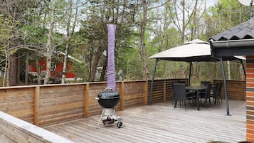 A wooden deck with a barbecue grill, outdoor furniture, and a pergola.