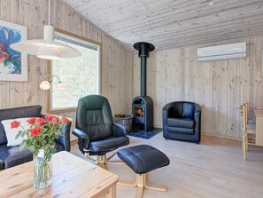 A cozy living room with a fireplace, leather furniture, and a wooden interior. - 4 Person Holiday Home in Nexo (Nexø)