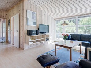 A modern living room with a wooden wall, a television, a sofa, and a coffee table. - 4 Person Holiday Home in Nexo (Nexø)