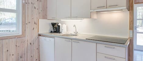 A compact kitchen with white cabinets, a built-in dishwasher, and a window providing natural light.