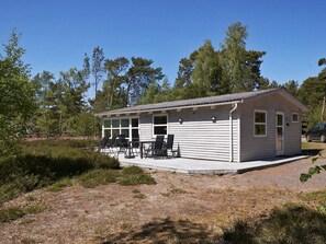 A small cabin with a porch, outdoor seating, and a gravel driveway. - 4 Person Holiday Home in Nexo (Nexø)