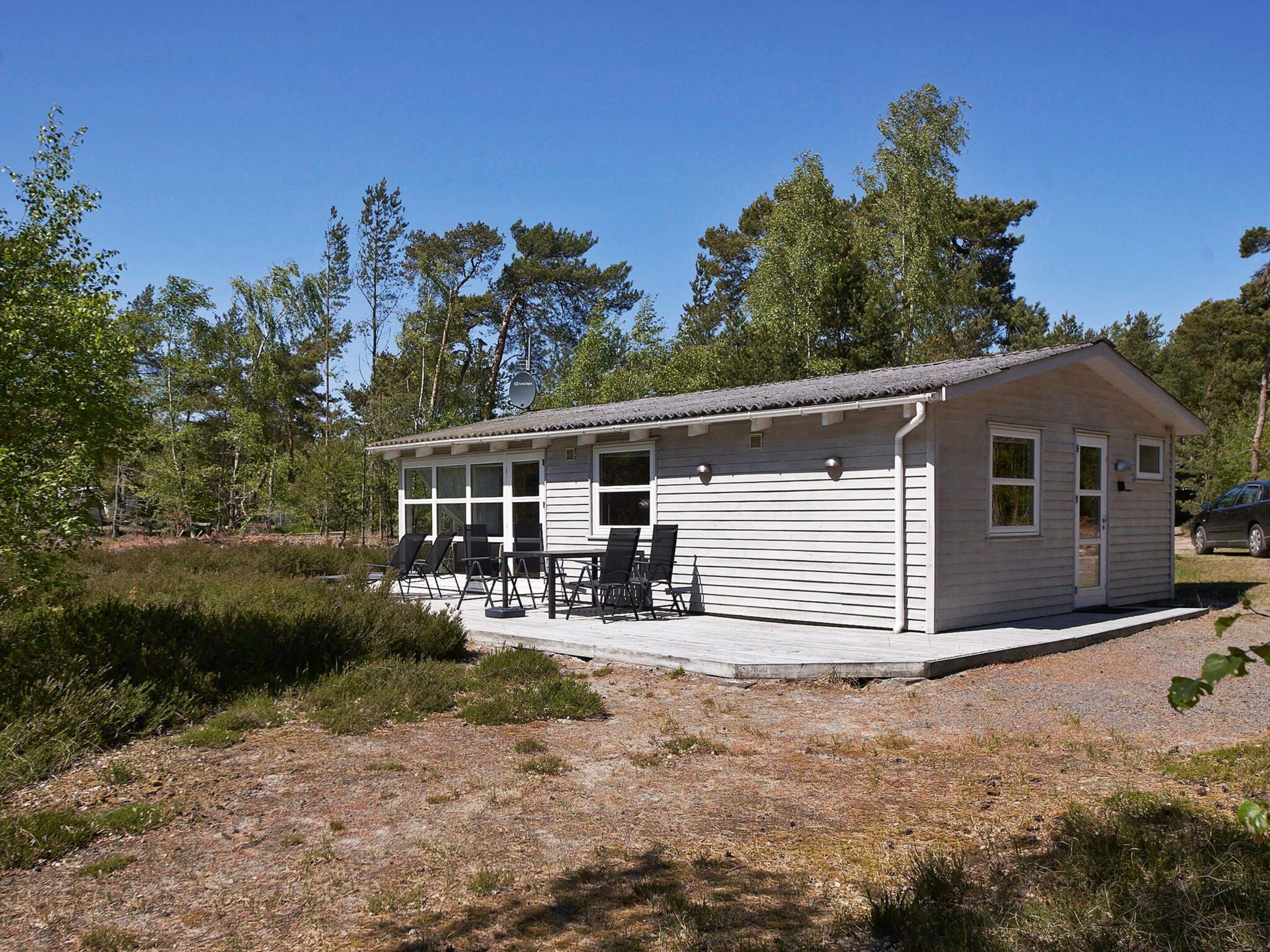 A small, single-story cabin with a porch and outdoor seating area.