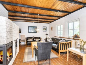 En hyggelig stue med pejs, sofa, spisebord og et vindue, der lukker naturligt lys ind.