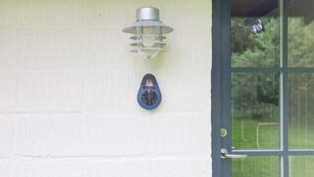 A white wall with a metal light fixture and a blue object.
