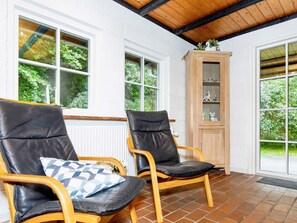 A room with two leather chairs, a wooden cabinet, and large windows. - 6 Person Holiday Home in Bindslev (Bindslev)