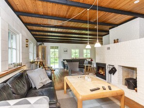 A cozy living room with a fireplace, wooden beams, and a sofa. - 6 Person Holiday Home in Bindslev (Bindslev)