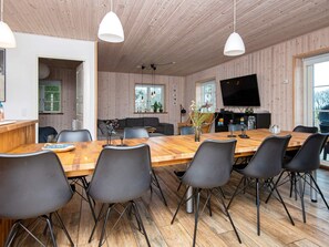 A modern kitchen with wooden cabinets, a large wooden table, and black chairs. - 10 Person Holiday Home in Glesborg (Glesborg)
