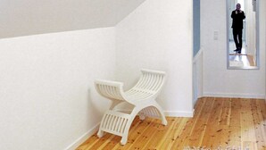 A hallway with wooden flooring, white walls, and a white chair. - Holiday Home in Holeby (Holeby)