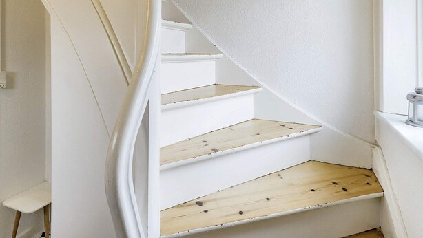 A white staircase with wooden steps and a white wall. - Holiday Home in Holeby (Holeby)