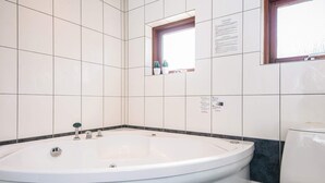 Une salle de bain avec une grande baignoire, des toilettes et une fenêtre.