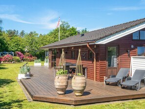 A wooden cabin with a deck, outdoor seating, and potted plants. - 4 Star Holiday Home in Ulfborg (Ulfborg)