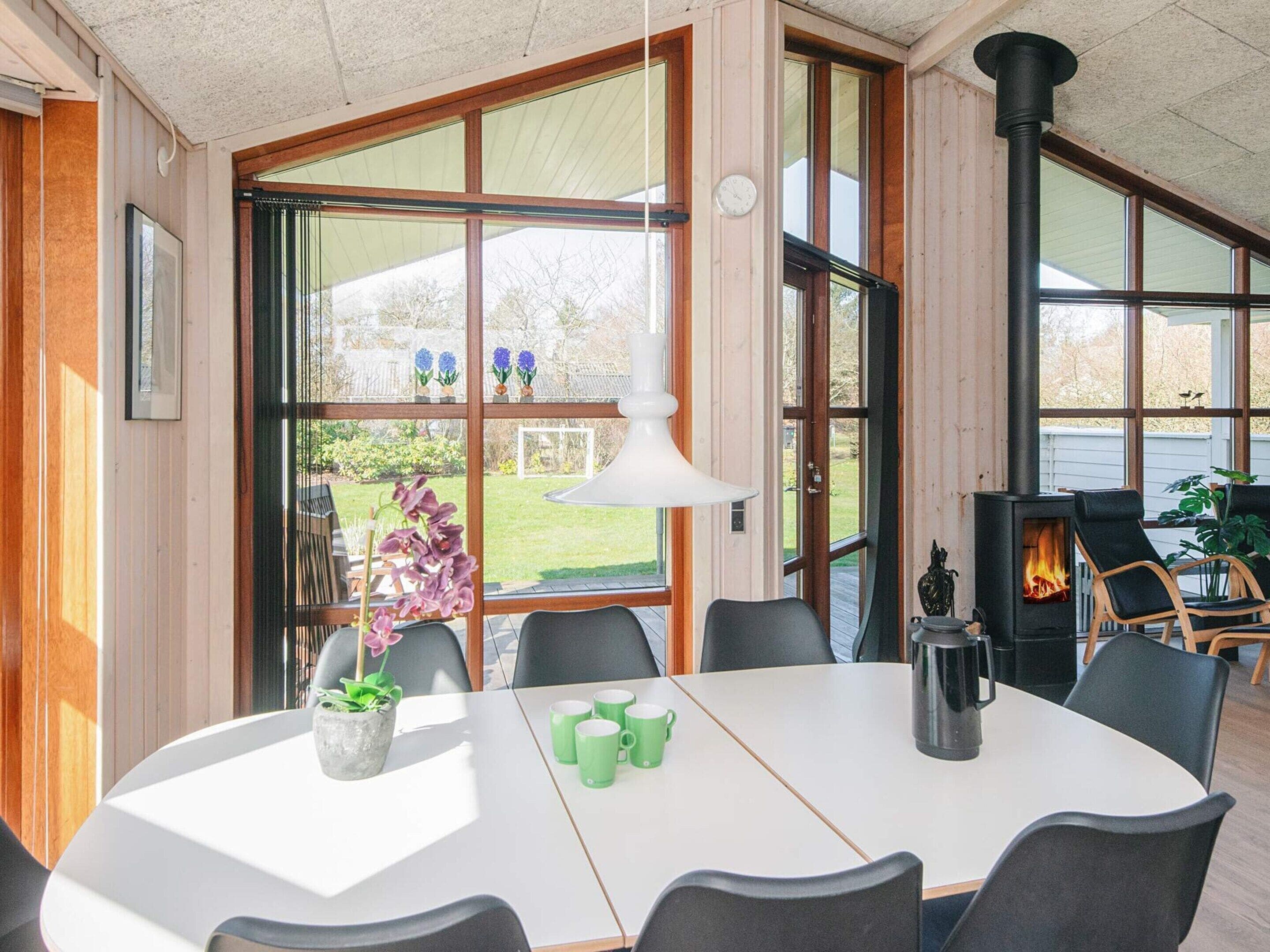 A modern interior with a large open-plan living area, a fireplace, and a dining table with chairs.