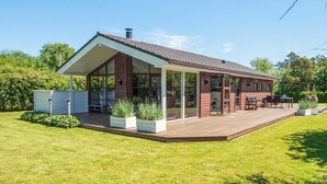 Une maison moderne dotée d’une grande terrasse, d’un patio couvert et d’une piscine.