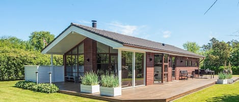 A modern house with a large deck, a covered patio, and a swimming pool.