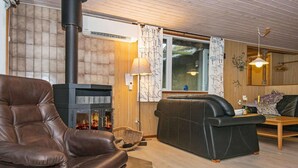 A cozy living room with a leather armchair, a sofa, a fireplace, and a wooden floor. - 6 Person Holiday Home in Romo (Rømø)