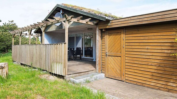 A wooden building with a covered patio area and a garage. - 6 Person Holiday Home in Romo (Rømø)