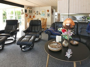 A modern living room with leather sofas, a round coffee table, and a dining area with wooden chairs. - 6 Person Holiday Home in Hadsund (Hadsund)