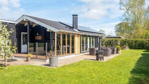 Ett modernt hus med en stor glasveranda, en skorsten och en välskött gräsmatta.