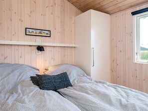 A bedroom with a bed, a white wardrobe, a framed picture on the wall, and a window. - 5 Star Holiday Home in Sjolund (Sjølund)