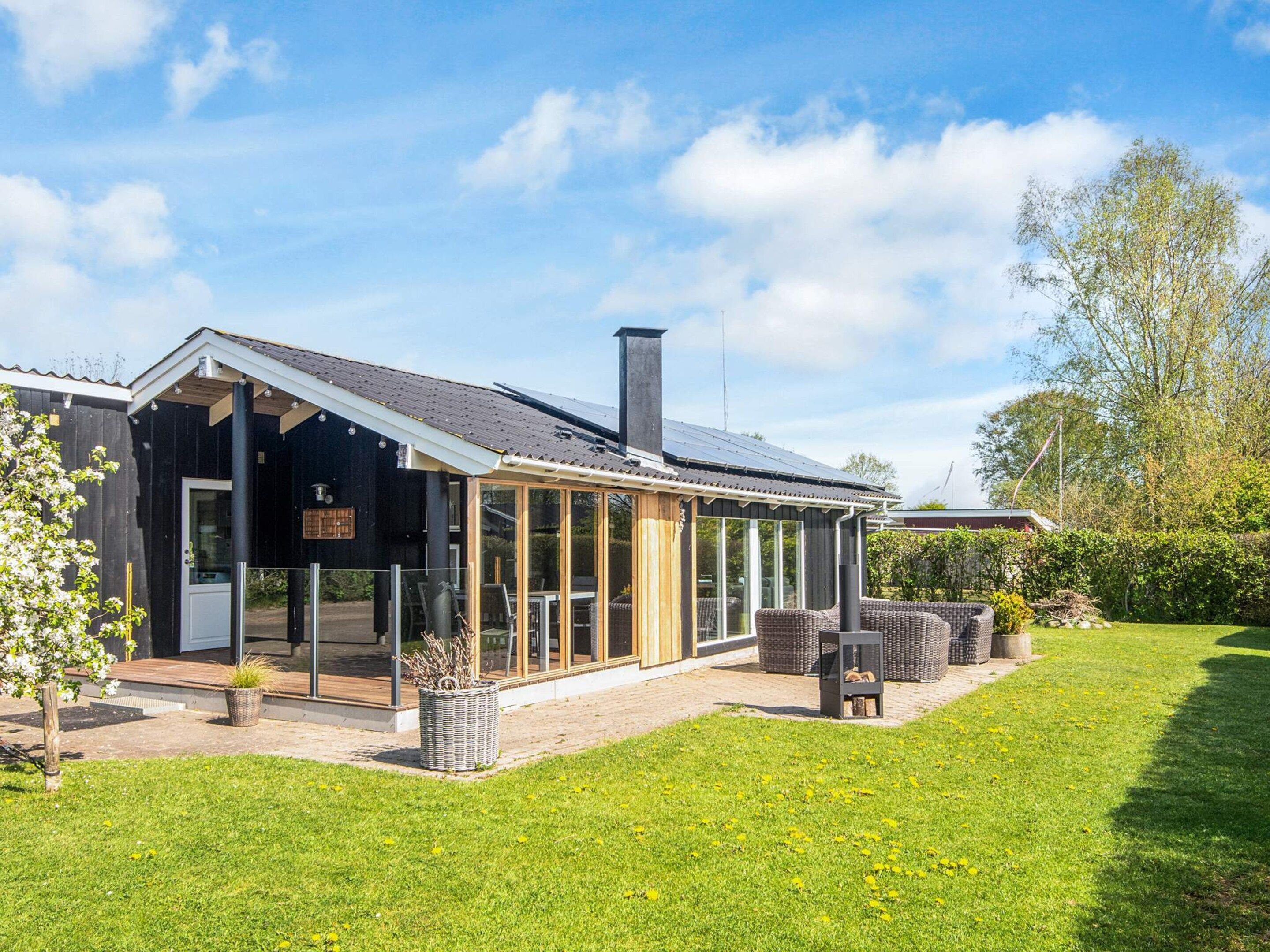 A modern house with a large glass extension, a chimney, and a well-maintained lawn.