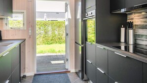 A modern kitchen with dark cabinetry, a built-in oven, and a window overlooking a garden.