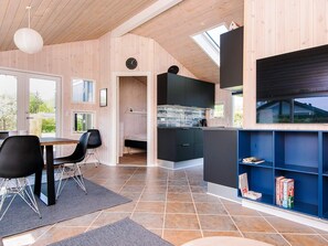A modern interior with a dining area, kitchen, and bookshelves. - 5 Star Holiday Home in Sjolund (Sjølund)