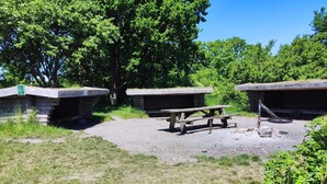 A picnic area with a wooden table and benches, surrounded by stone structures and greenery.