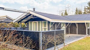 A modern house with a covered porch, a large deck, and a fenced yard. - 4 Star Holiday Home in Hals (Hals)