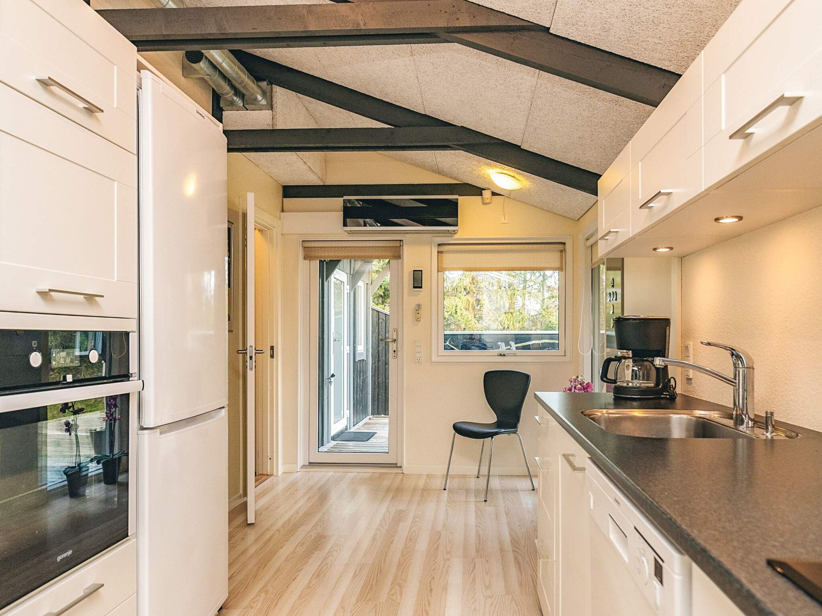 A modern kitchen with white cabinetry, a built-in oven, a coffee maker, and a sink.