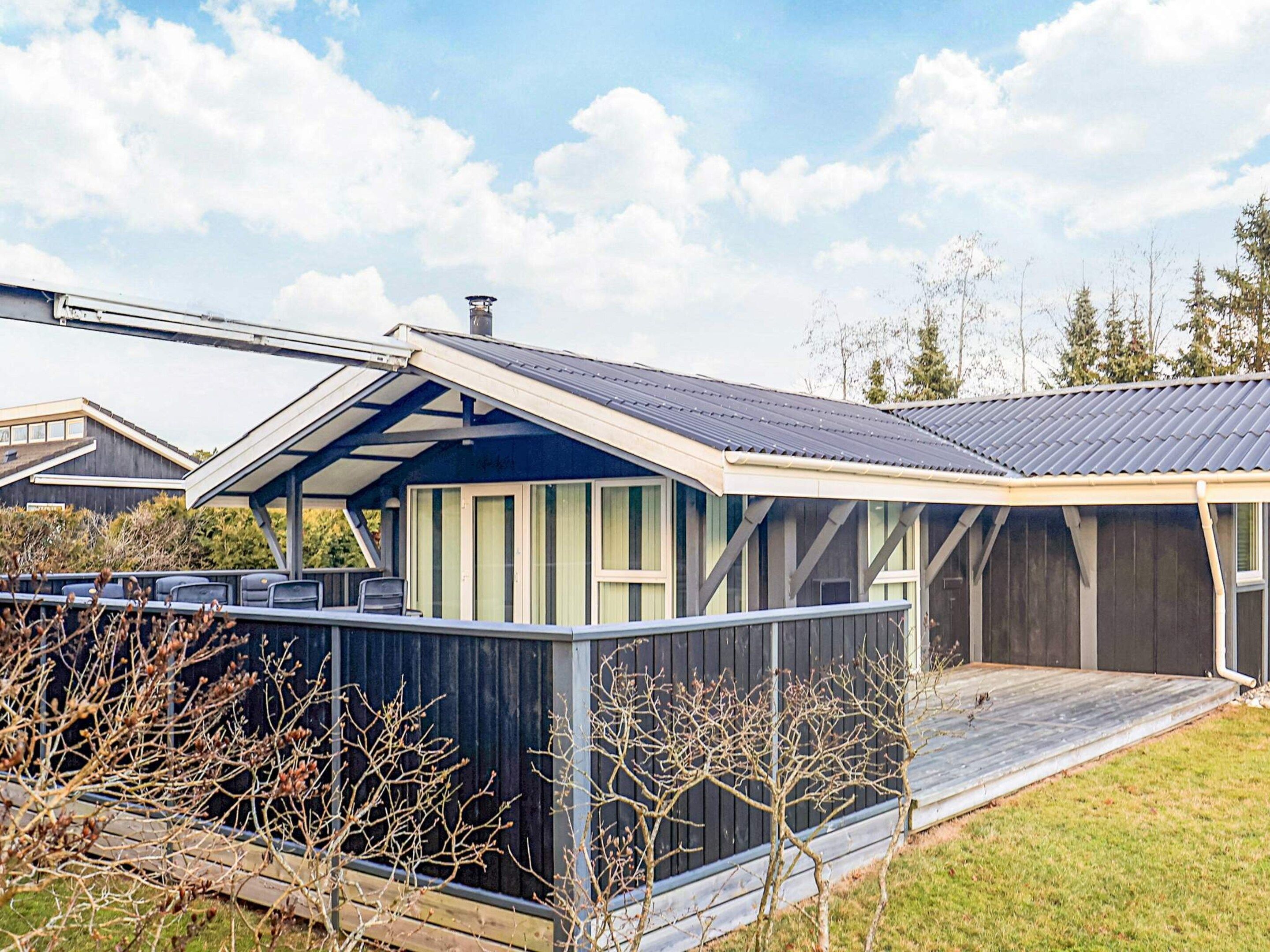 A modern house with a covered porch, a large deck, and a fenced yard.