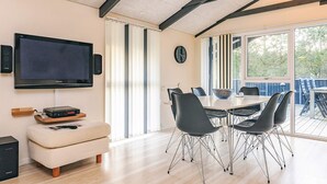 A modern dining area with a large table, black chairs, and a television mounted on the wall. - 4 Star Holiday Home in Hals (Hals)