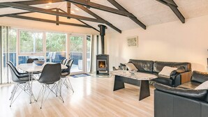 A spacious living room with a high ceiling, a fireplace, a dining area with chairs, and a sofa. - 4 Star Holiday Home in Hals (Hals)