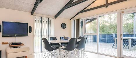 A modern dining area with a marble table, black chairs, a television, and a clock on the wall.