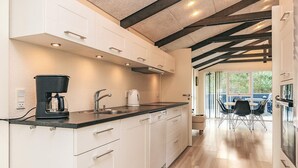 A modern kitchen with white cabinets, a black countertop, and a coffee maker. - 4 Star Holiday Home in Hals (Hals)