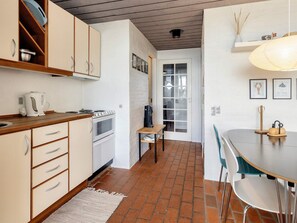 A compact kitchen with a stove, oven, and a small dining area with a table and chairs.