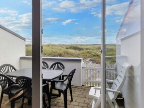 A patio with a table and chairs, a white fence, and a view of the landscape.