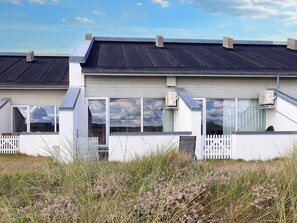 A modern building with a flat roof, large windows, and a white picket fence. - 6 Person Holiday Home in Brovst (Brovst)