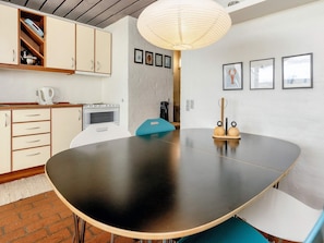 Una cocina moderna con una mesa redonda grande, armarios de madera y una lámpara colgante.