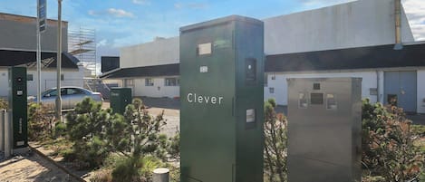 A utility box labeled 'Clever' with a street lamp nearby, set against a building with a clear sky.