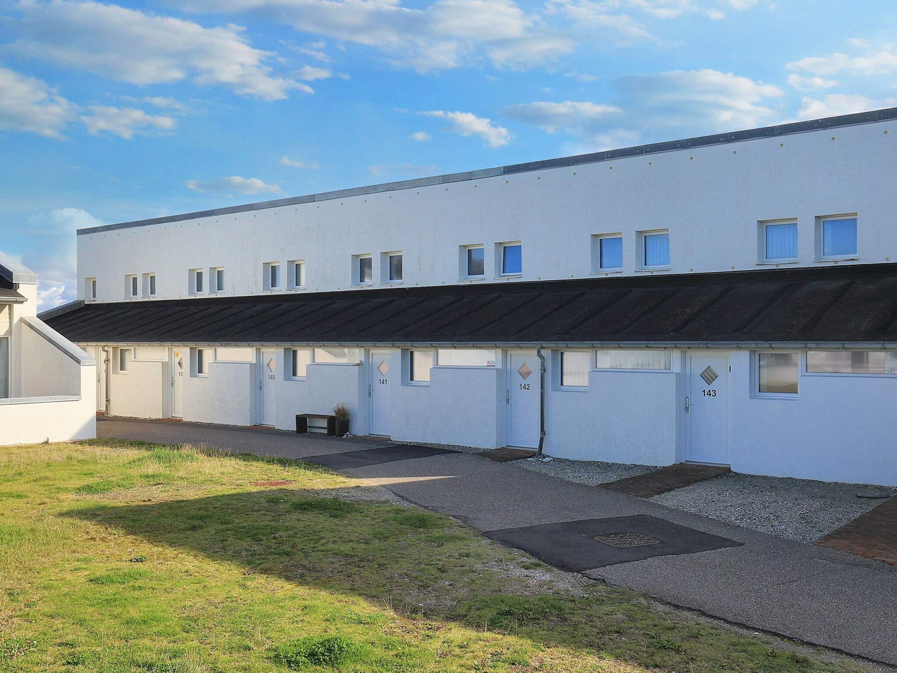 Un edificio moderno con porte numerate, un tetto piatto e un cielo sereno.