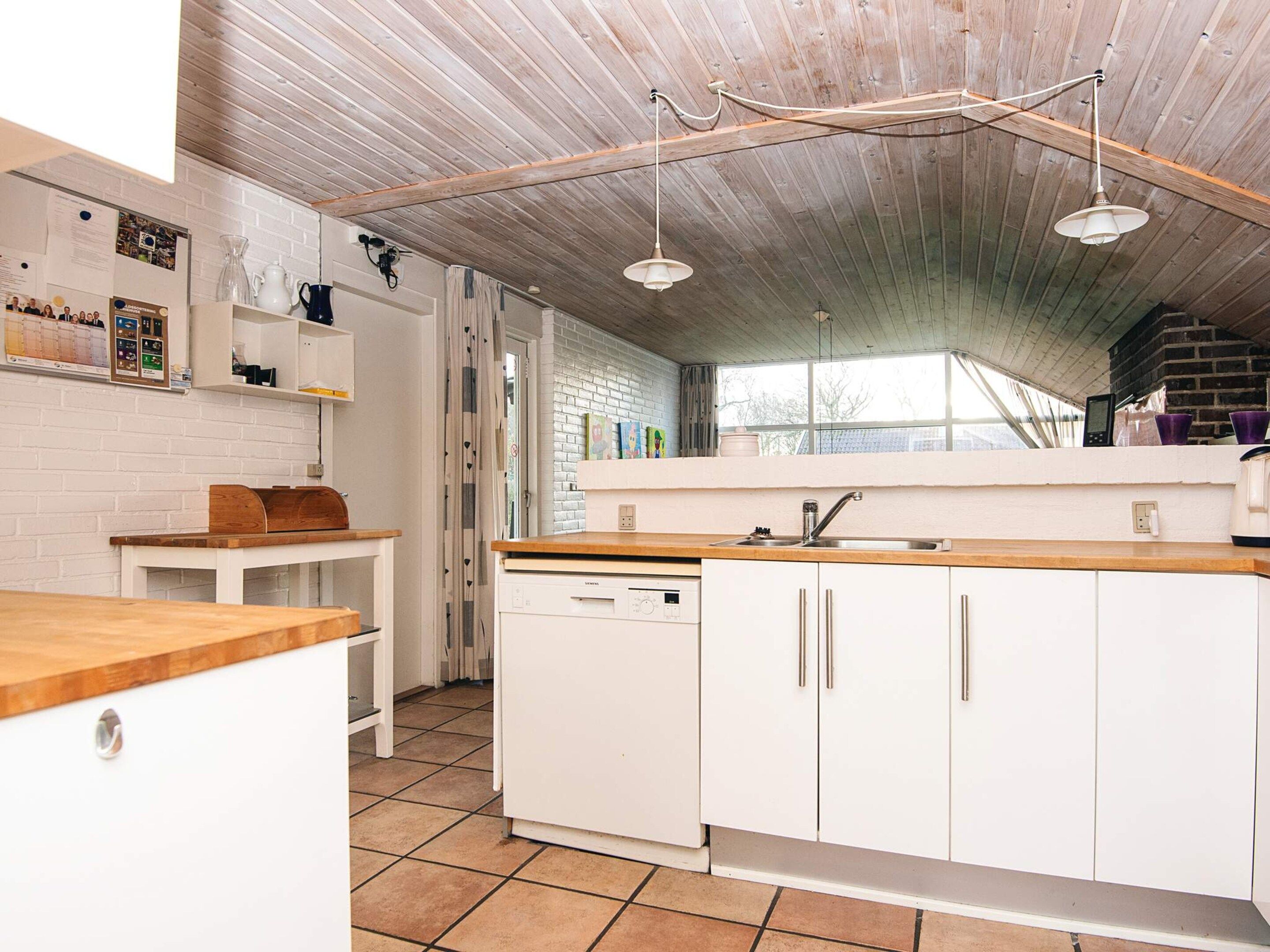 A kitchen with white cabinets, a wooden countertop, and a built-in dishwasher.