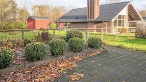 A residential building with a brick facade, a large chimney, and a fenced yard with neatly trimmed bushes and a paved driveway. - 4 Person Holiday Home in Hemmet (Hemmet)
