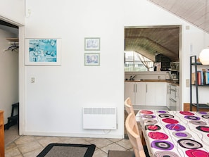 A compact living space with a kitchenette, a dining area with a patterned tablecloth, and artwork on the walls.