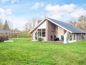A single-story house with a sloped roof, large glass windows, and a brick exterior.