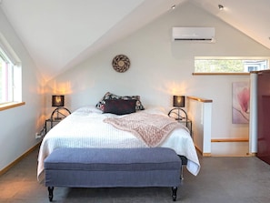 A bedroom with a bed, bedside lamps, an air conditioner, a wall decoration, and a window. - Holiday Home in Onsala (Gottskar)
