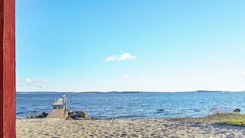 A beach with a small structure, clear sky, and calm sea.