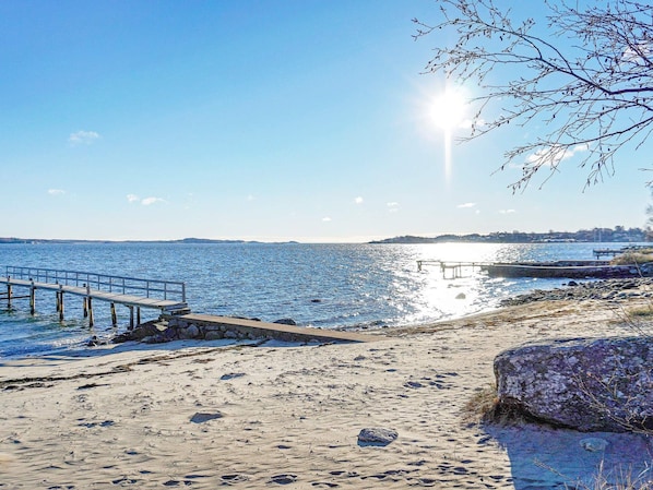 A beach with a wooden pier extending into calm waters, a rocky shoreline, and a clear sky. - Holiday Home in Onsala (Gottskar)