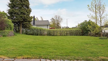 A well-maintained grassy yard with a stone pathway leading to a house with a chimney.
