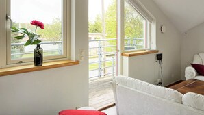 A room with a large window, a white sofa, and a wooden table. - Holiday Home in Onsala (Gottskar)